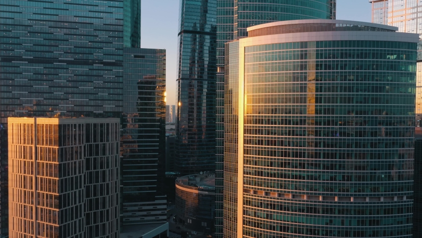 Moscow city glass skyscrapers drone tilt up shot, close to the buildings windows, sun reflection in the windows. Moscow International Business Center at the sunset, evening Royalty-Free Stock Footage #1060961716
