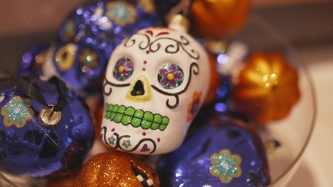 FHD Video of a Decorative White Skull on top of blue skulls and orange pumpkins Ornaments for the Day of the Dead and Halloween Celebration