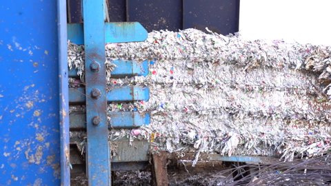 shredded milk cartons on conveyor belt at recycling plant getting put into bales