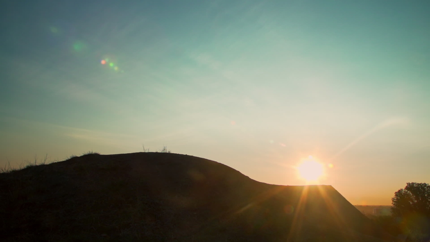 Man on mountain bike launches over a dirt ramp in a bike park into the sky. His silhouette passes in front of the sun. Shot in glorious slow motion at 240 fps. Royalty-Free Stock Footage #1060965193