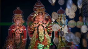 Decorated Durga Puja pandal with Durga idol, Out of focus hanging coins , Durga Puja festival at night. Slow mo HD footage shot under colored light.