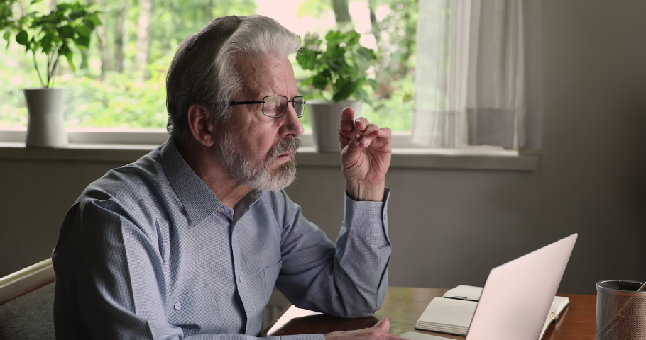 Middle aged 55s man wear eyeglasses sit at desk typing on computer, journalist create new article solve issues distantly by e-mail, do remote work from home. Older generation modern tech usage concept Royalty-Free Stock Footage #1060968205