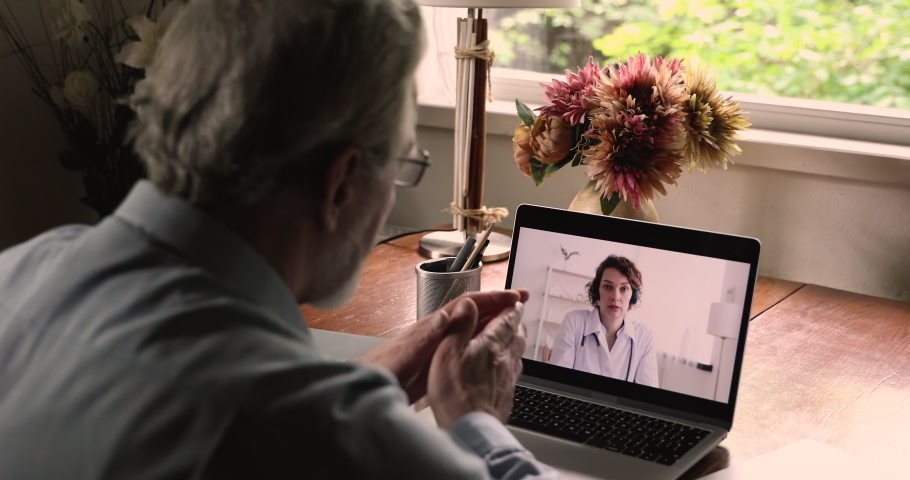 Laptop screen view over old 50s male shoulder during talk with medical worker, patient asks female doctor, receive medical aid online due quarantine coronavirus pandemic outbreak, telemedicine concept Royalty-Free Stock Footage #1060968214