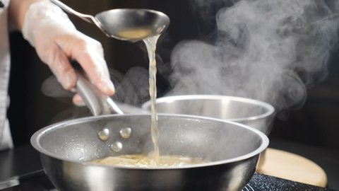 Fish broth being poured out of ladle. Traditional Italian cuisine and recipe, Slow motion. Italian seafood restaurant. Cooking risotto on stove. Full hd