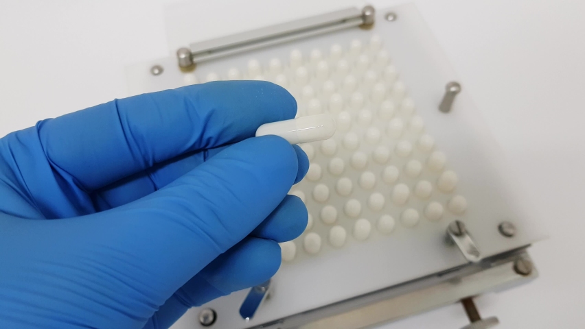 Inspection of white capsule by pharmacist at laboratory. Close up