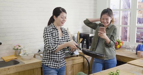 slow motion of two asian chinese women couple having fun and giving high five together in modern kitchen.