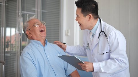 Asian man doctor give help support handicapped old patient happy sitting in wheelchair, doctor caregiver or nurse assist take care of smiling senior disabled grandfather, elderly healthcare concept.