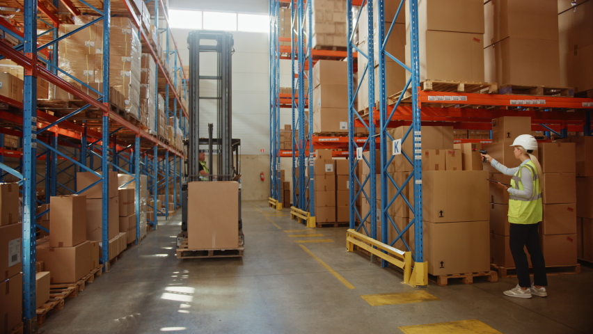 Retail Warehouse full of Shelves with Goods in Cardboard Boxes, Workers Scan and Sort Packages, Move Inventory with Pallet Trucks and Forklifts. Product Distribution Delivery Center. Static Shot | Shutterstock HD Video #1060977037