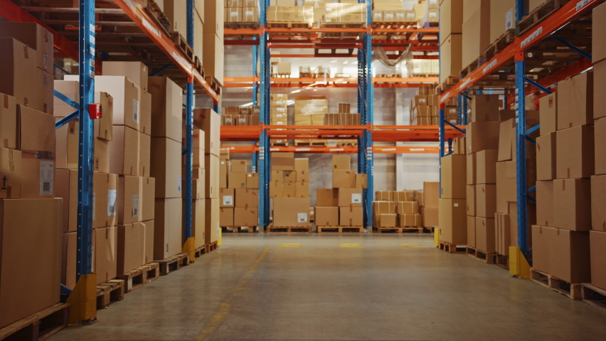 In Big Retail Warehouse Moving Sunlight Illuminates Shelves with Cardboard Boxes. Forklift Driving in Logistics, Distribution Center with Products Ready for Global Shipment, Customer Delivery Royalty-Free Stock Footage #1060977055