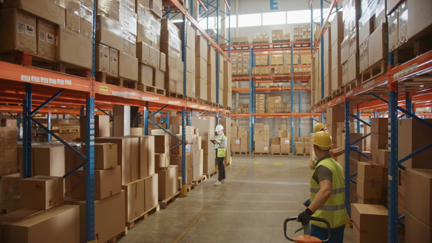 Retail Warehouse full of Shelves with Goods in Cardboard Boxes, Workers Scan and Sort Packages, Move Inventory with Pallet Trucks and Forklifts. Product Distribution Logistics Center. Descending Shot Royalty-Free Stock Footage #1060977073