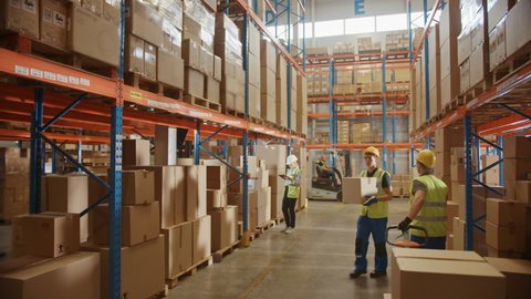 Retail Warehouse full of Shelves with Goods in Cardboard Boxes, Workers Scan and Sort Packages, Move Inventory with Pallet Trucks and Forklifts. Product Distribution Logistics Center. Descending Shot