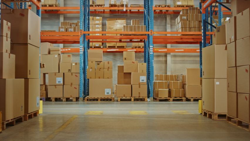 High-Tech Futuristic Warehouse: Manager Scans Packages for Inventory, Delivery in the Background Worker Wearing Advanced Full Body Powered exoskeleton, Walks with Heavy Pallet full of Cardboard Boxes Royalty-Free Stock Footage #1060977187