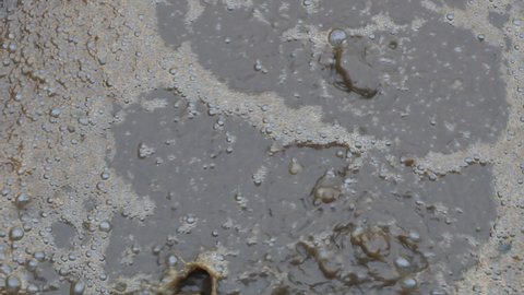 Rest methane and air create thick brown foam on the sediment tank in town sewage treatment company. Background of lots of bubbles on dirty water