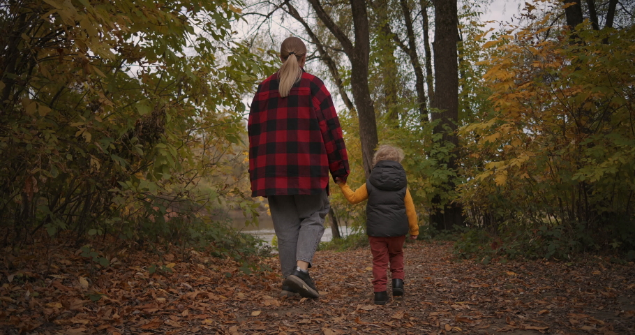Walking at autumn forest, woman with little son are walking to lake, rear view, enjoying nature and relaxing at weekend | Shutterstock HD Video #1060979143