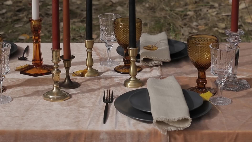 outdoor table setting with beautiful tableware with glass goblets and candles Royalty-Free Stock Footage #1060980352