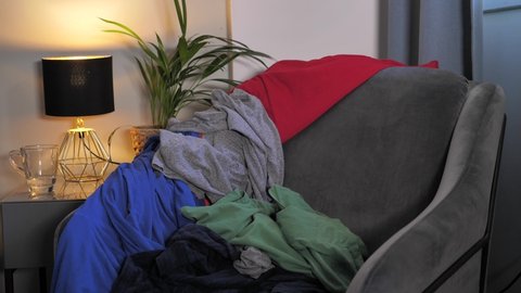 Unfolded cloths are thrown in a mess on an armchair in a mess