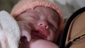 4K: Newborn baby with Mother in hospital bed / Maternity ward. The child has a hat on and is close by her mum. Stock Video Clip Footage
