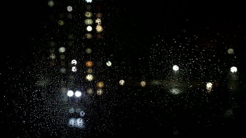 Raindrops on the glass of the window, outside the window the street driving cars, bad weather. Background, copy space for text, night