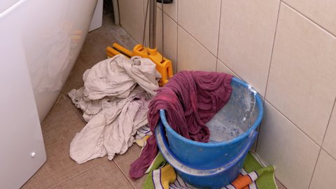 Throw Dirty Things, Rags into Bucket in Bathroom. Scattered Rags. Cleaning bathroom. Putting things in order. Chaos, disorder.