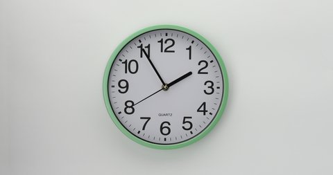 Quartz wall clock on a white background. The clock shows five minutes to two. 4K DCI video. 