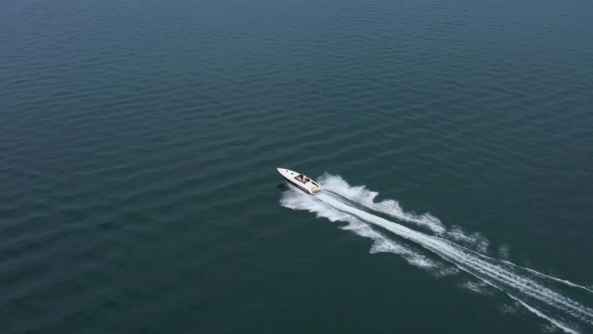 Drone view of a boat  the blue clear waters. Top view of a white boat sailing to the blue sea. Large speed boat moving at high speed. Travel - image. | Shutterstock HD Video #1060988821