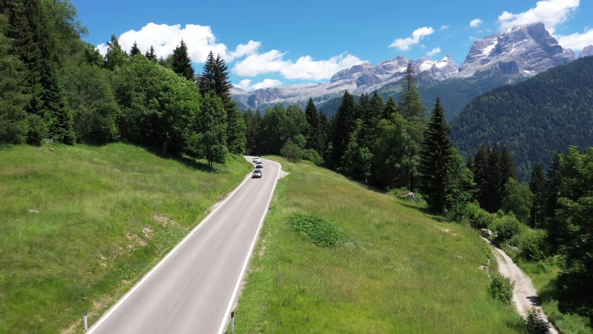 Highway in the Alps. Top view of the movement of cars in the mountains. Aerial view of car driving down country road through rural rolling hills at sunset	 Royalty-Free Stock Footage #1060989421