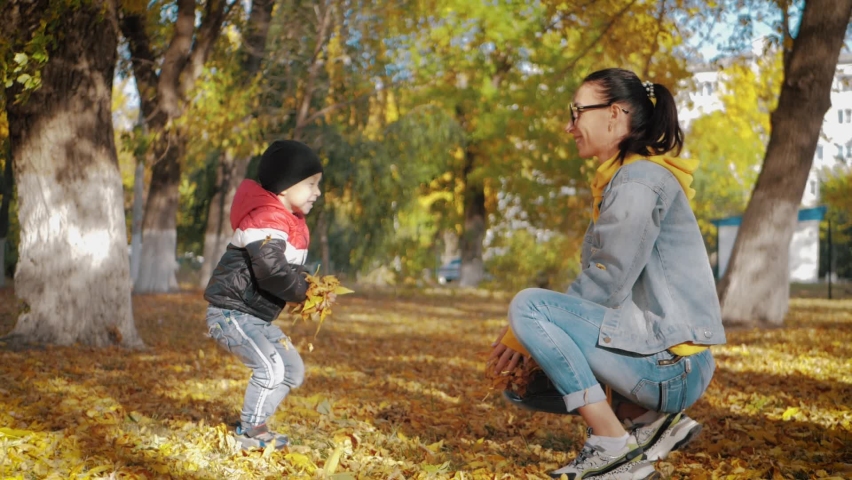 Mom playing with son in autumn park. Happy moments together. Family in the autumn park.
