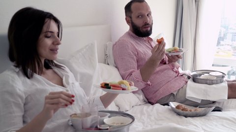 Young couple eating and talking during breakfast at bed
