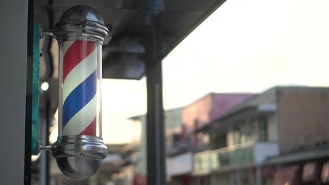 A barber pole calling for people at street. Vintage barbershop. Salon.