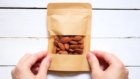 Place a pouch product full of almond . On a white wood scene