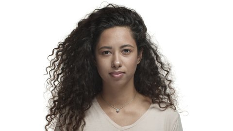 Close-up of attractive flirty girl with long curly hairstyle, wearing beige t-shirt, smiling and flicking hair with confidence, standing over white background
