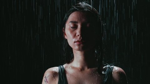 Woman with closed eyes under the rain portrait. Girl has calmness and satisfaction on her face, acceptance of herself and the situation. Young lady made an important decision. Concept of fear.