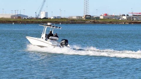 PORT ARANSAS, TX - 27 FEB 2020: Fishing boat with outboard motor and two people, accelerates as it leaves the marina on a sunny day,