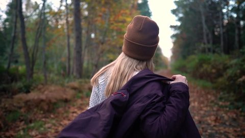 A young blonde girl puts on her winter jacket as it's starts getting colder outside.