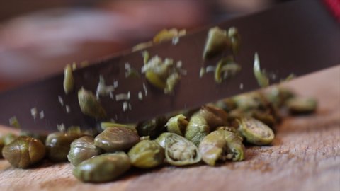 Chopping Capers with Knife On Wooden Chopping Board