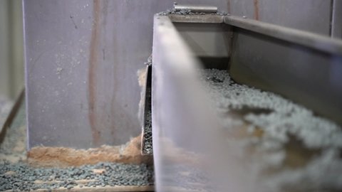 cinematic shot of recycled grey plastic pellets being washed in a conveyer