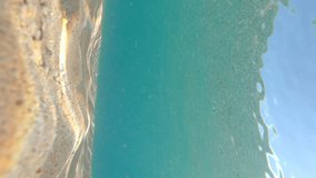Transparent blue water on the beach in Spanish Costa Brava. A man swimming freestyle swim. Vertical footage use as mobile background