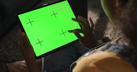 african american woman using tablet computer with green screen watching movie enjoying entertainment looking at chroma key on mobile touchscreen device at home horizontal orientation