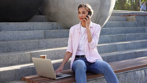 Businesswoman sitting stairs summer park using laptop and smartphone Business person working remote. Outdoor. Successful Young european caucasian woman freelancer meeting online 
