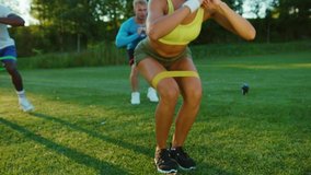 Group of sportive young adults mixed-race athletes doing squats and stretching exercises with resistance bands for healthy body. Active lifestyle. Bodybuilding. - Powered by Shutterstock - Get 15% off with code: PIKWIZARD15