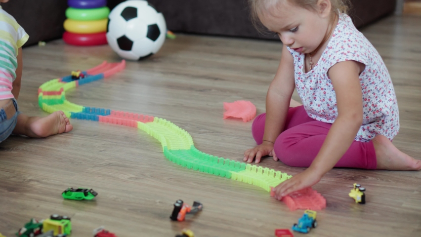 Childhood, games, upbringing and development concept - general plan of little children boy brother and girl sister baby play with magic road in kid playroom. Siblings have fun at home on quarantine
