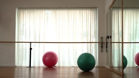 Pink and turquoise balls roll along brown wooden gym floor