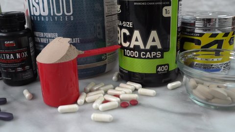 Los Angeles / United States - 01 09 2020: Loose pills, powders and bottles of sports and exercise nutrition supplements. Slider shot 