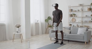 Futuristic sport training. African american guy in VR headset doing lunges forward exercise at home, watching online video tutorial