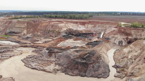 Opencast mining quarry with lots of machinery. Iron ore quarry from bird's eye view. Open pit for gold mining. Open pit mine coal mining, dumpers, quarrying extractive industry stripping work
