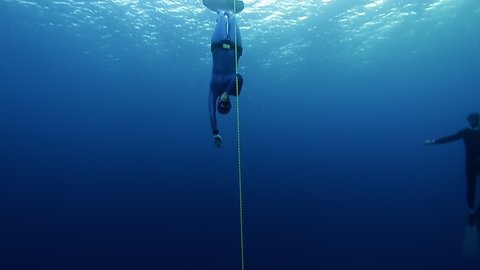 Woman freediver descends into depth along the rope