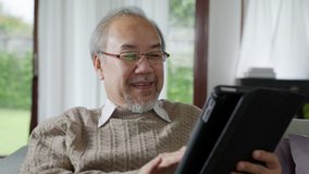 Candid of old asian retired man using tablet computer to transfer money online or financial payment and read text, smile or laugh with happy and positive. Senior asian with digital technology concept - Powered by Shutterstock - Get 15% off with code: PIKWIZARD15