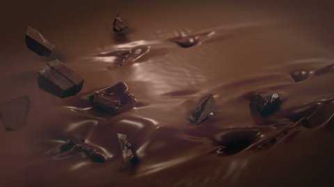 Pieces of Chocolate Falling Into Liquid Chocolate in 4K Super slow motion