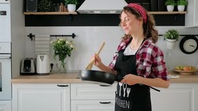 Carefree happy young woman housewife dancing alone cooking meal