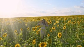 Video portrait of a beautiful young pregnant woman in a sunflower field in summer at sunset
